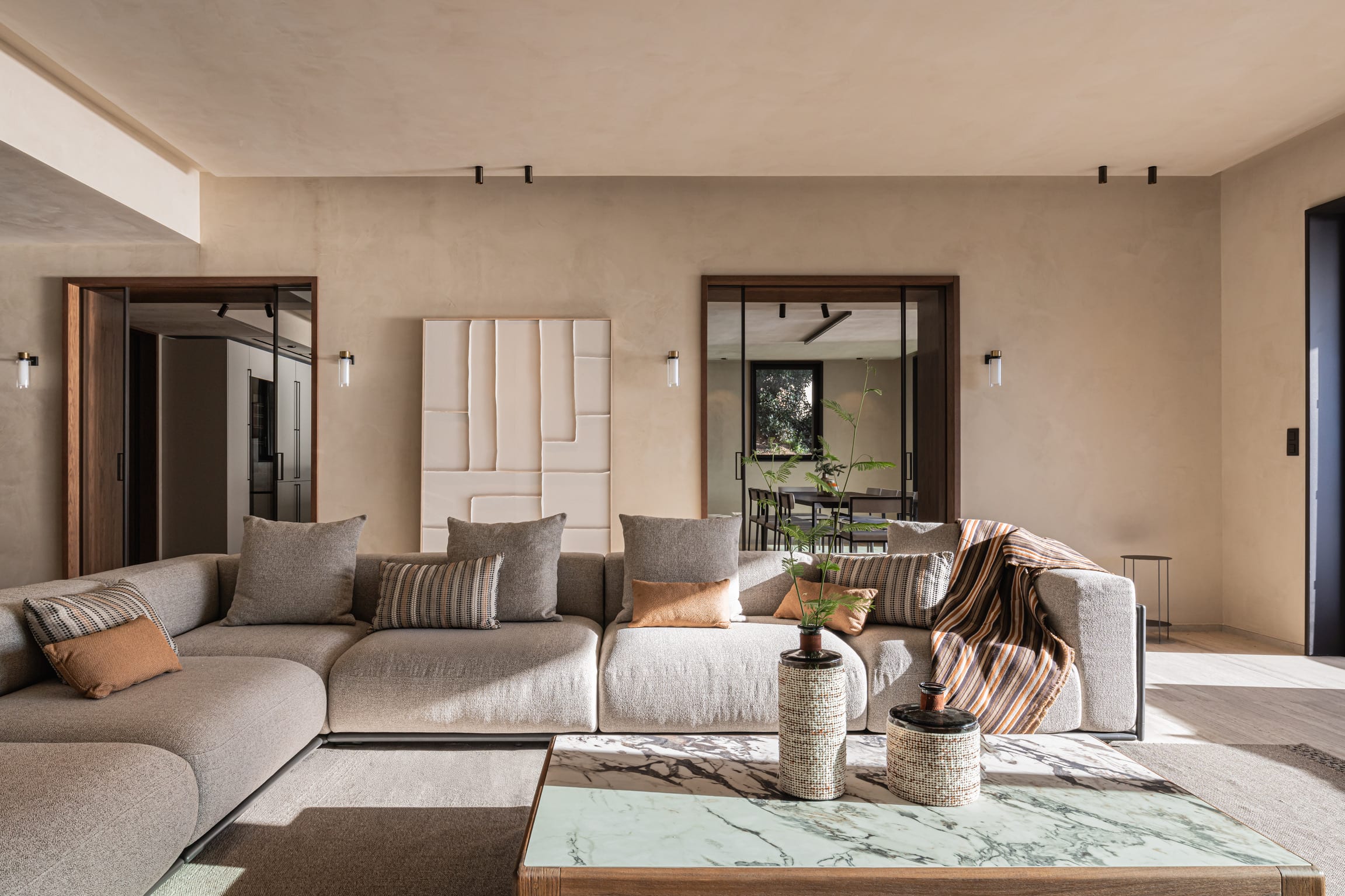 Séjour d'une villa contemporaine rénovée : béton ciré, canapé d'angle et menuiseries en noyer sur mesure